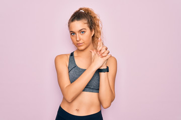 Obraz premium Young beautiful blonde sportswoman with blue eyes doing exercise wearing sportswear Holding symbolic gun with hand gesture, playing killing shooting weapons, angry face
