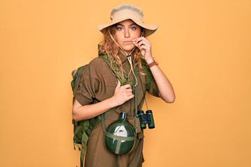 Young blonde explorer woman with blue eyes hiking wearing backpack and water canteen mouth and lips...