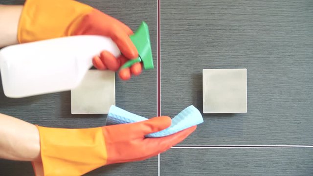Nettoyage par d&eacute;sinfection du coronavirus en pulv&eacute;risant un antisepsie assainissent sur une poign&eacute;e de porte de placard m&eacute;tallique, muni de gant de protection.