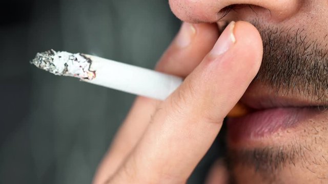 young man smoking a cigarette close-up. smoke fire light. boy smokes. man's lips. addiction tobacco smoker poison