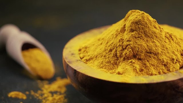 Turmeric or turmeric powder in a wooden bowl blowing in the wind. Cooking ingredients, flavor.