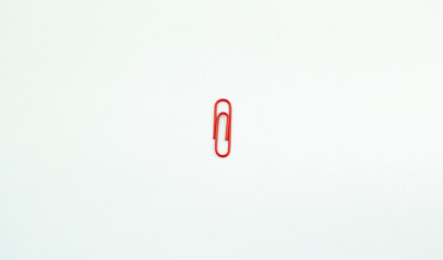 Red paper clip isolated on a pure white background.
