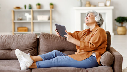 Cheerful senior woman using tablet and listening to music.