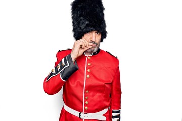 Middle age handsome wales guard man wearing traditional uniform over white background mouth and...