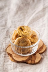 Dried figs in glass cup on grey napkin background