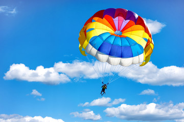 Gliding using a parachute on the background of cloudy blue sky. - obrazy, fototapety, plakaty