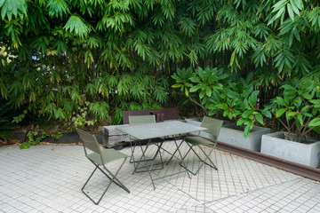Outdoor seats in a courtyard surrounded by green leafy plants. 