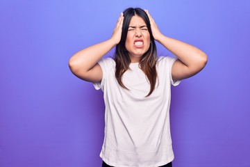 Fototapeta premium Young beautiful brunette woman wearing casual t-shirt standing over purple background with hand on head, headache because stress. Suffering migraine.