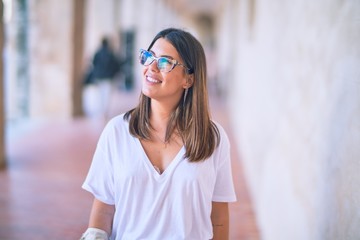 Young beautiful woman smiling happy and confident. Standing with smile on face at the town street