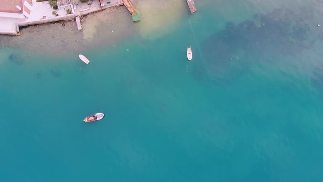 drone flying above adriatic sea with turquoise water boats on pier city at seashore