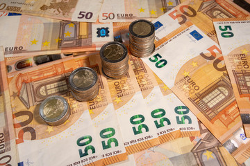 many euro banknotes and stack of coins