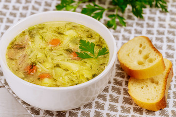 Chicken noodle soup with parsley and bread.