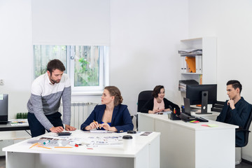 Office workers in an open space, doing different things, colleagues chatting, discussing projects, working on PCs, doing some paperwork. Coworking concept