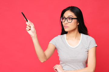 Student showing sth by pen. Studio shoot on red background.