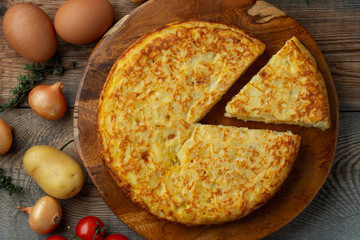 Spanish omelette with potatoes and onion, typical Spanish cuisine. Tortilla espanola. Rustic dark background. Top view