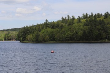 Fototapeta na wymiar A view of a kayaker on a beautiful New Hampshire lake in summer.