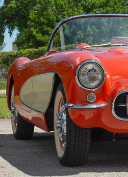 vintage car of the 50s. Front of a classic American car. Antiquity in colors. Orange classic car. Headlights, chrome, wheels.
