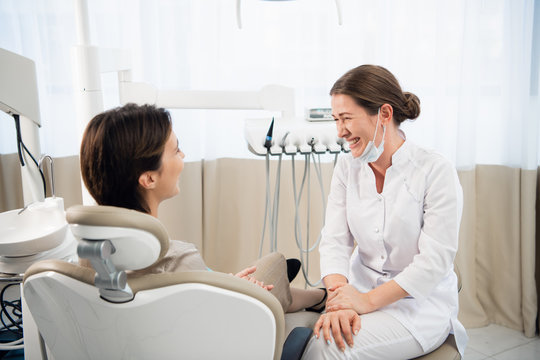 Young female doctor chatting to her patient in her dental office and laughing
