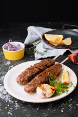 Fried sausages with the addition of herbs, vegetables, garlic, lemon and onions on the dish. Grilling food, bbq, barbecue. Homemade sausages from turkey fried in a frying pan