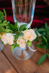 Glasses of champagne decorated with flowers stand on a wooden table during a wedding ceremony. Wedding decorations. Closeup details of a wedding decor
