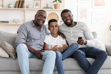 Happy African Grandfather, Father And Son Watching TV At Home Together
