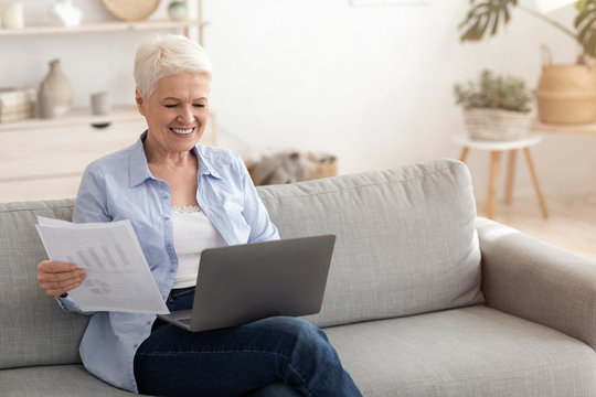 Smiling Elderly Woman Working With Laptop And Documentation At Home