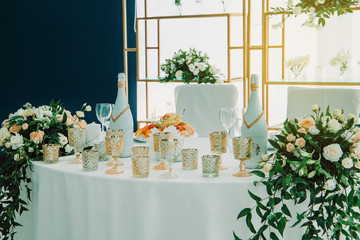 Wedding table of the bride and groom decorated with flowers and candles. Indoor wedding ceremony.