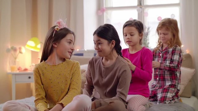 Group of small girls friends playing on bed on slumber party.