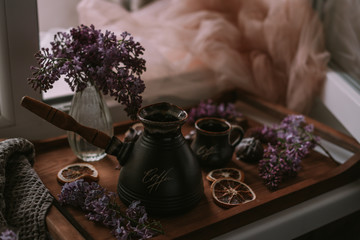 Still life of lilac flowers, coffee and chocolate on wooden tray