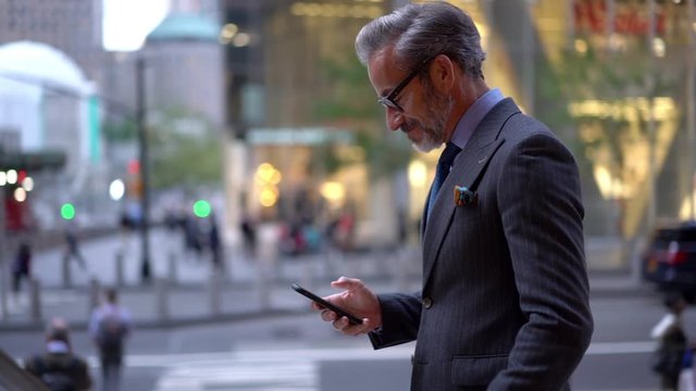 Slow motion effect of happy businessman reading received text message and celebrating news about approved project, successful male entrepreneur in formal suit using cellphone for chatting
