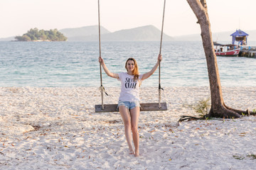 Beautiful girl sitting on swing on the seaside