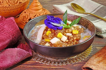 Thai dessert : Sago Pearl with sweet corn , dressing with fresh coconut milk, topping with young coconut meat, decorated with blue pea flower and pandan leaf. Selective focus.