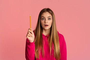 Obraz premium Shocked teenager girl with open mouth raises pencil up