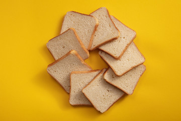 The bread on the table view from above in the form of a circle. Square white bread in square slices.
