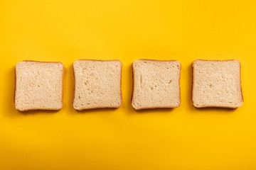 The bread on the table top view. Bright yellow background with square slices of bread for Breakfast or lunch and dinner.