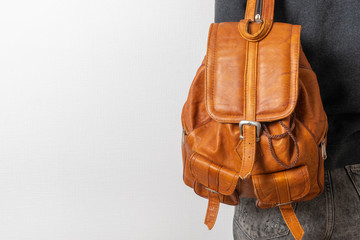 Back of woman with brown leather backpack against white wall background. travel concept