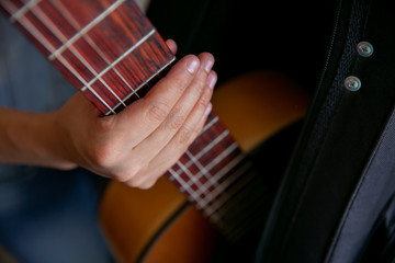 Woman observes and removes a classic brown guitar from a black case