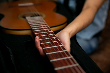 Woman observes and removes a classic brown guitar from a black case