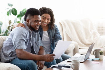 Happy black couple managing family budget at home together