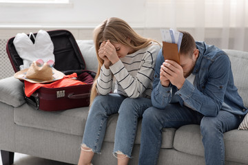 Desperate couple sitting near packed suitcase at home