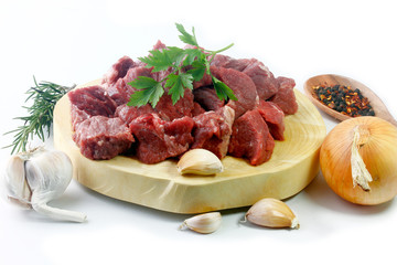 pile of cube chopped pile raw diced beef cubes with spices on wooden board isolated over white background