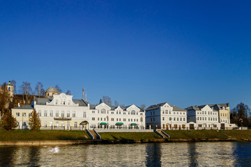 Old buildings by the river. Reflection of white houses in the water.
