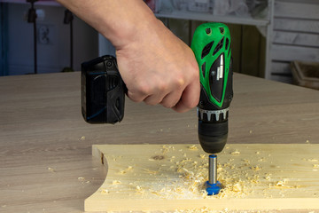 Carpenter drilling wooden board in workshop. Instruments, profession