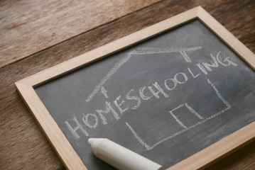 Selective focus of a chalkboard written with Homeschooling on wooden background.