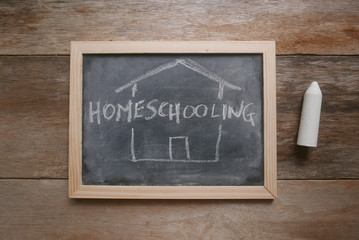 Top view of a chalkboard written with Homeschooling on wooden background.