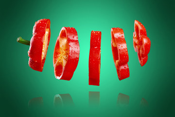 Sliced red bell pepper with reflection, isolated on a green and fresh background