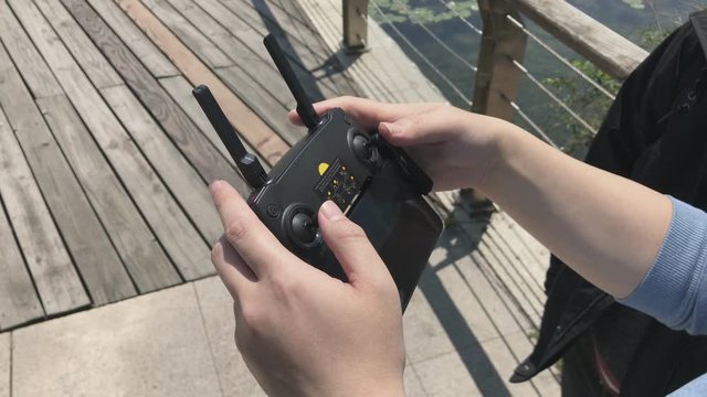 Man operating the remote drone controller on the ground and camera tilt up to the sky to reveal the drone he is controlling. The sunny sky with no cloud. The remote transmitter of unmanned flight