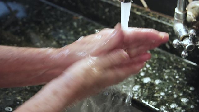 washing elderly hand with soap and water