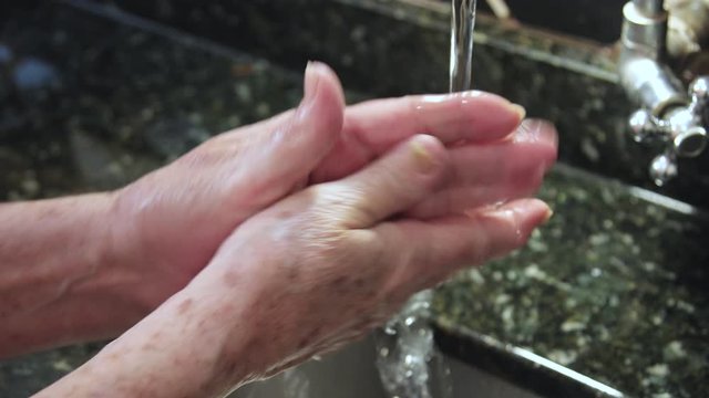 washing elderly hand with soap and water