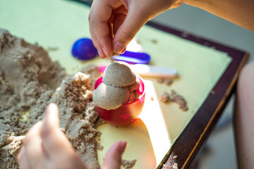 Child's hand playing with kinetic sand in preschool. The development of fine motor concept....